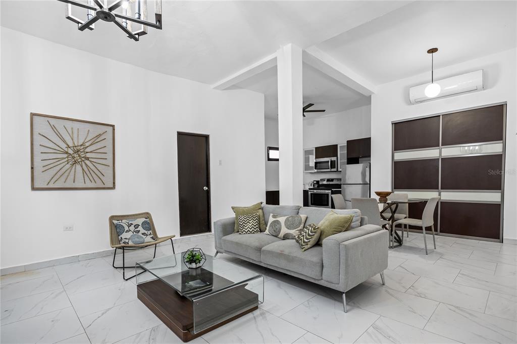 A modern living room features white tile floors, a gray sofa, and an open kitchen — 152 LUNA, SAN JUAN, PR