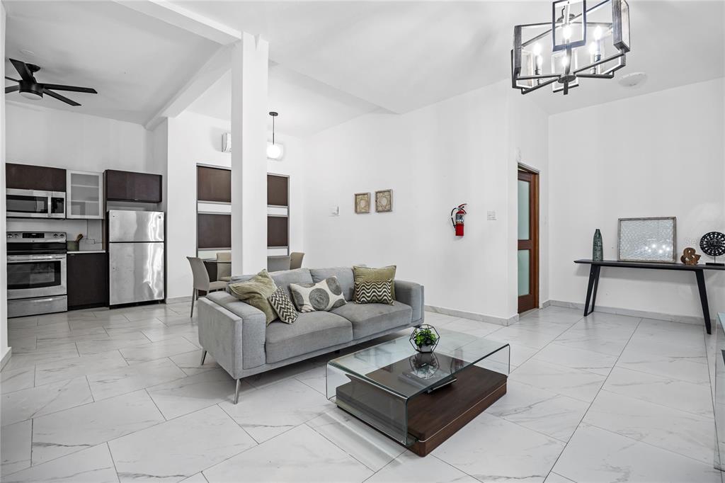 A bright, open-concept living room and kitchen featuring white tile floors and modern furnishings — 152 LUNA, SAN JUAN, PR