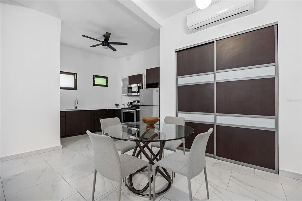 A dining area with a glass table and four chairs sits before a modern kitchen — 152 LUNA, SAN JUAN, PR