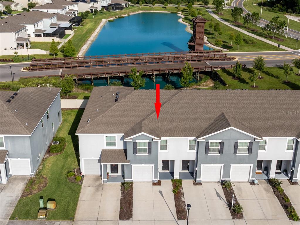An aerial view of a multi-unit townhouse building situated near a lake and bridge — 1817 HOVENWEEP ROAD, WESLEY CHAPEL, FL
