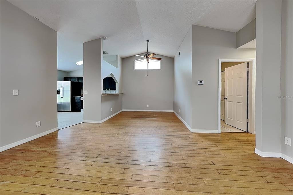 A living area with hardwood floors, vaulted ceilings, and a view into the kitchen — 13344 LARAWAY DRIVE, RIVERVIEW, FL