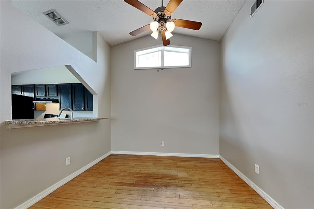 A dining area with wood flooring, a ceiling fan, and a pass-through to the kitchen — 13344 LARAWAY DRIVE, RIVERVIEW, FL