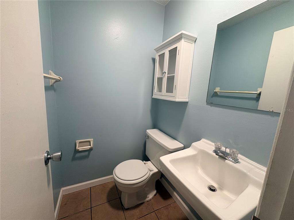 A small bathroom features light blue walls, a white vanity, a toilet, and wall-mounted cabinetry — 9080 GENEVA STREET, SPRING HILL, FL
