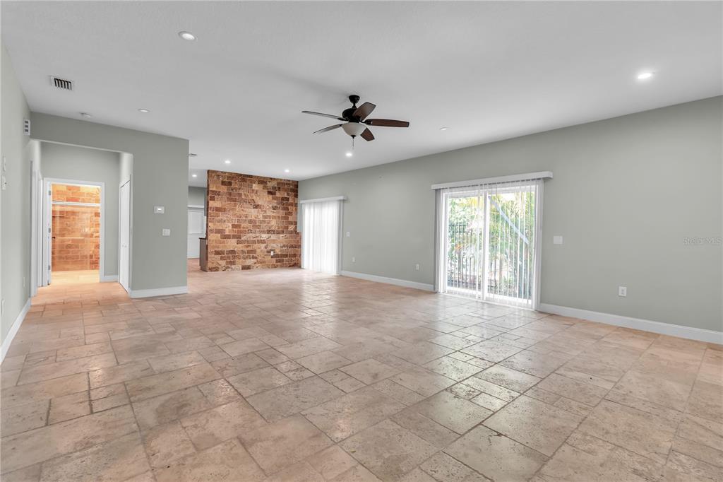 A spacious living room features light tile flooring, a stone accent wall, and sliding glass doors — 1536 25TH STREET, SARASOTA, FL