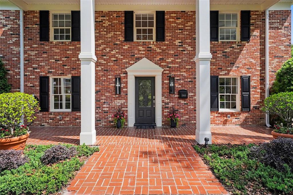 A brick house exterior features a front porch with white columns and a dark door — 37403 CHURCH AVENUE, DADE CITY, FL