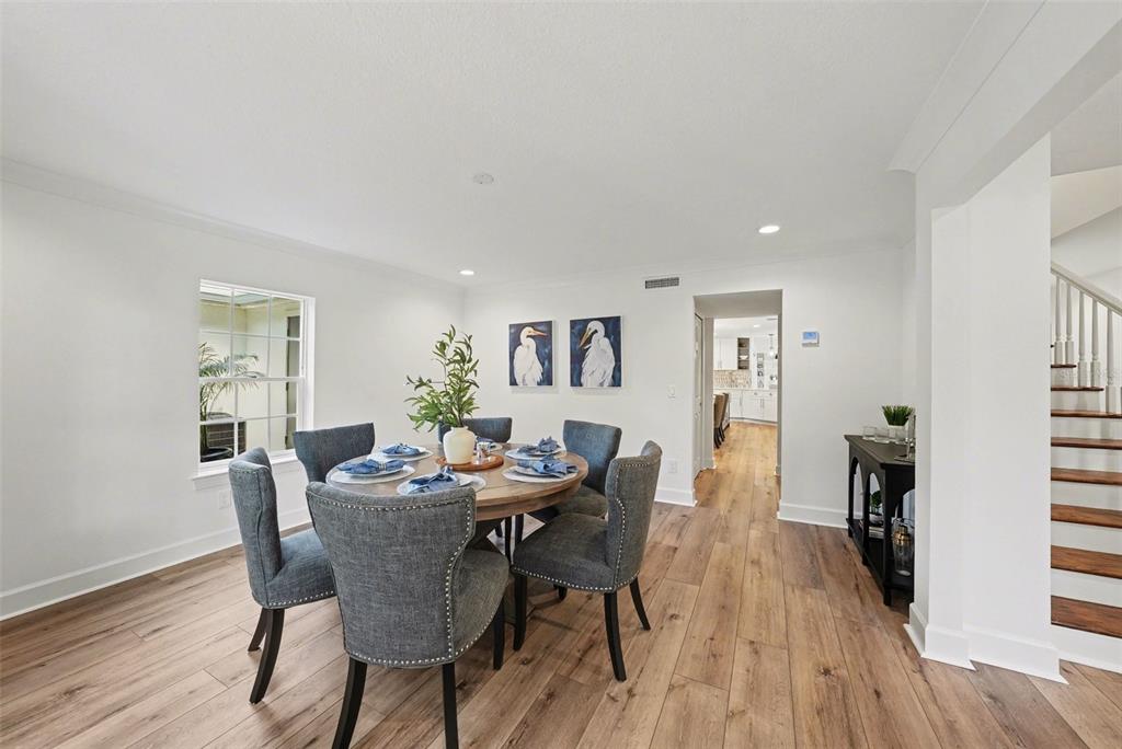A dining room features a round wooden table with blue chairs and wood-look flooring — 37403 CHURCH AVENUE, DADE CITY, FL