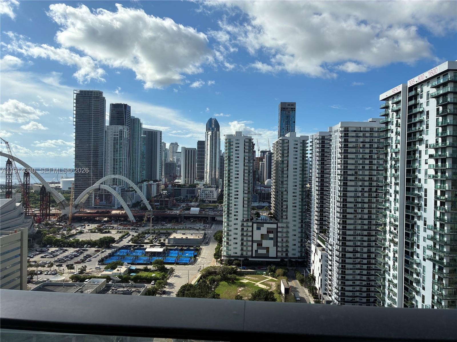 A bedroom features a blue tufted headboard, a red bench, and a balcony with city views — 1600 NE 1st Ave # 2508, Miami FL 33132, MIAMI, FL