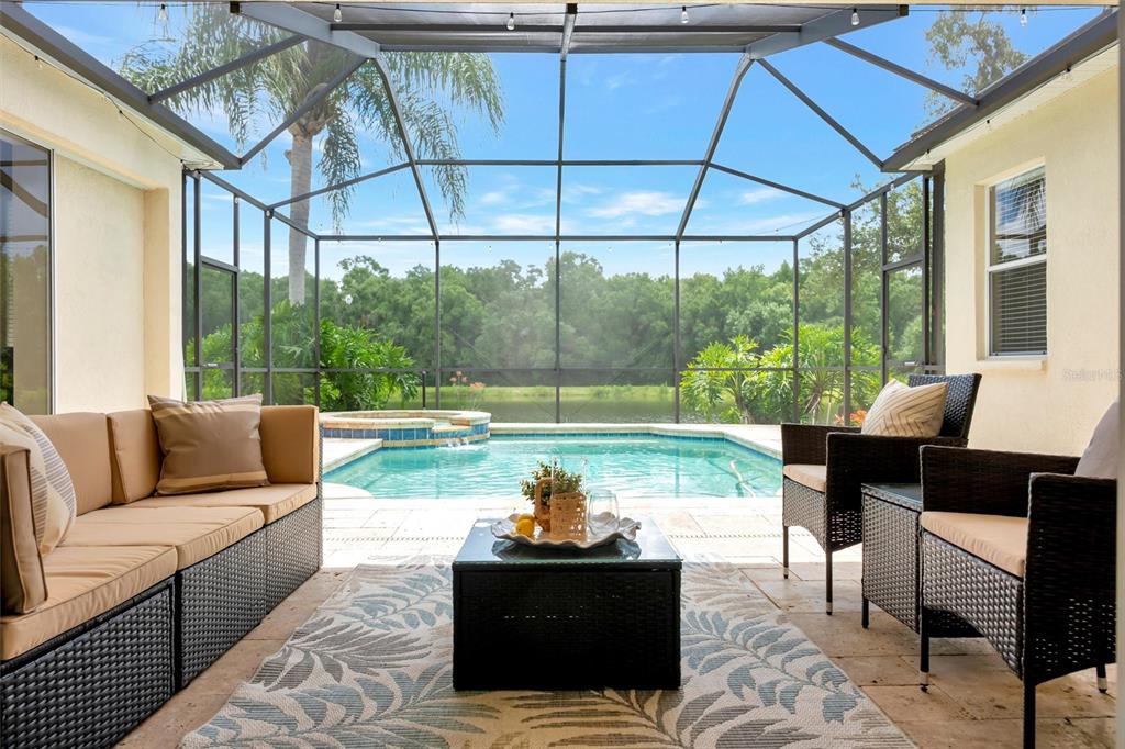 A screened-in patio features outdoor furniture, a pool, and a view of a lake — 8523 PORTAGE AVENUE, TAMPA, FL