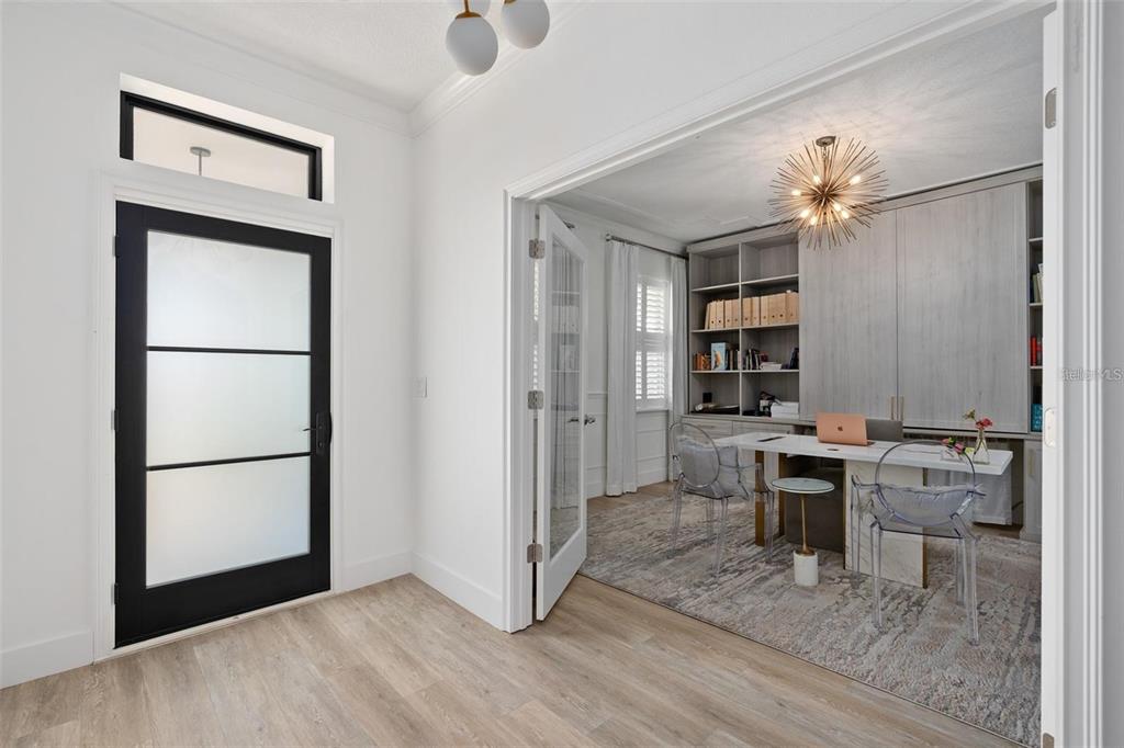 A bright entryway with a black-framed glass door leads into a home office with built-ins — 4509 PATRICIA ANN COURT, ORLANDO, FL
