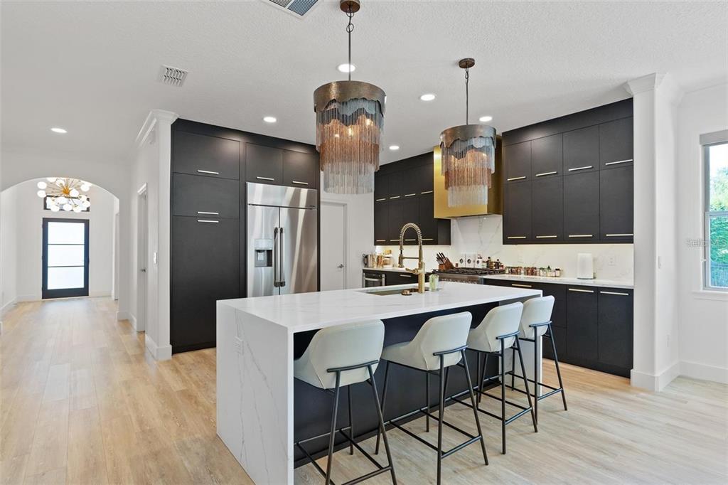 A modern kitchen features dark cabinetry, a white marble island, and two decorative chain-link pendants — 4509 PATRICIA ANN COURT, ORLANDO, FL