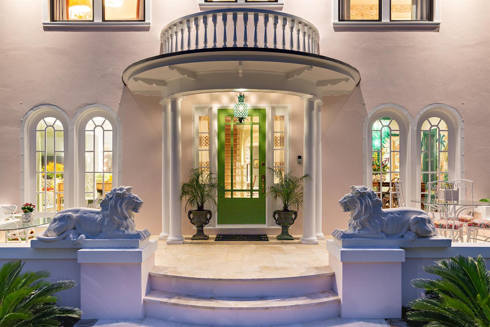The exterior of a pink house features a green front door, lion statues, and columns — 3101 Washington Road, West Palm Beach FL 33405, WEST PALM BEACH, FL