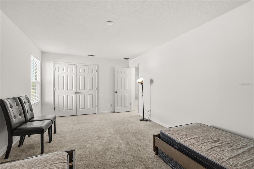 A carpeted bedroom features white walls, a double-door closet, and a single bed — 5277 ROYAL POINT AVENUE, KISSIMMEE, FL