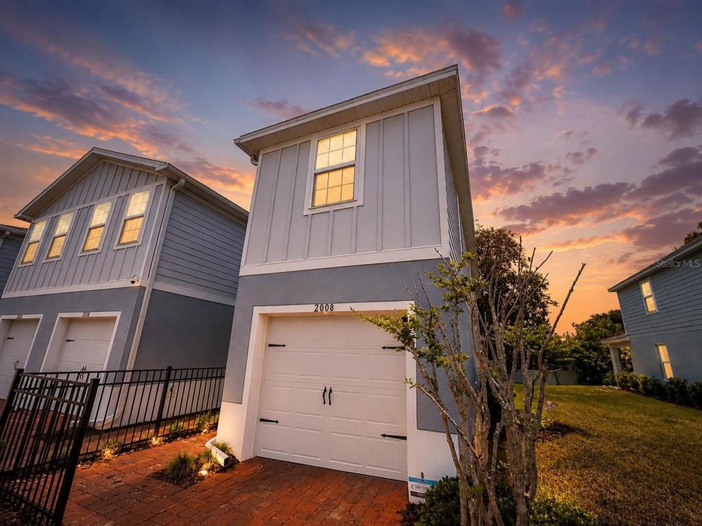 A two-story house with a white garage door and light blue siding at sunset — 2008 EDISON POINTE BOULEVARD, SOUTH DAYTONA, FL