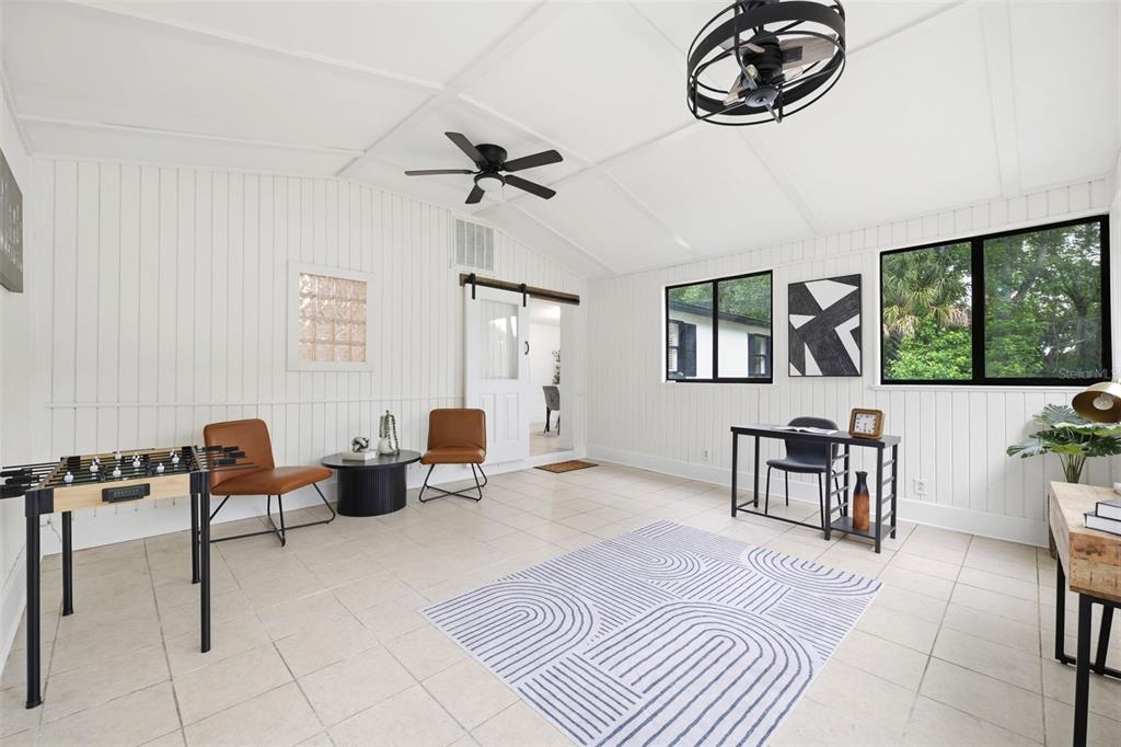 A bright sunroom features white paneled walls, tile flooring, a foosball table, and a desk — 7229 PLATHE ROAD, NEW PORT RICHEY, FL