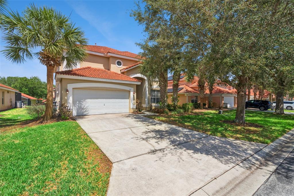 A two-story house with a white garage door, tan stucco walls, and a red tile roof — 143 CORDOVA AVENUE, DAVENPORT, FL
