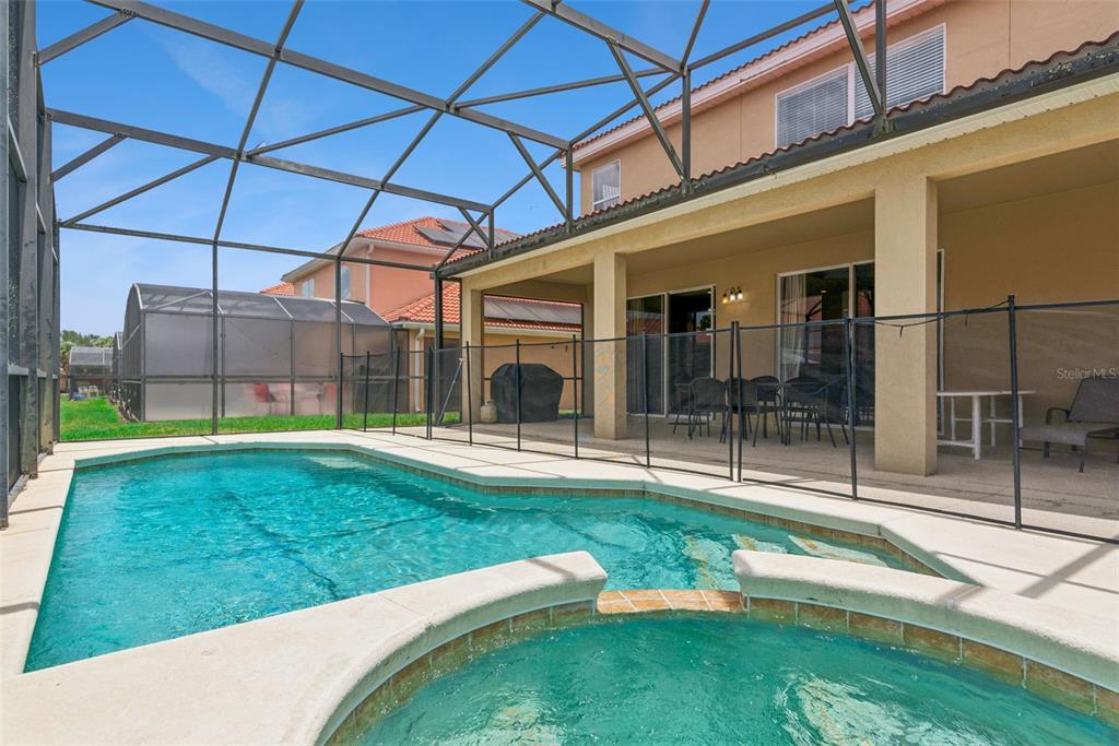 A screened-in pool and spa area with a covered patio and outdoor dining furniture — 143 CORDOVA AVENUE, DAVENPORT, FL