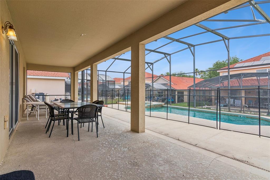 A covered patio features a dining set and a screened-in swimming pool with a safety fence — 143 CORDOVA AVENUE, DAVENPORT, FL