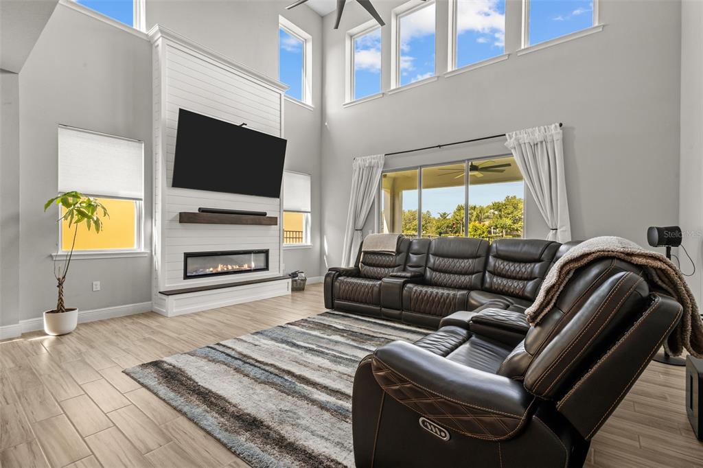 A living room features a tall fireplace, a large sectional sofa, and floor-to-ceiling windows — 14722 CARAVAN AVENUE, ODESSA, FL