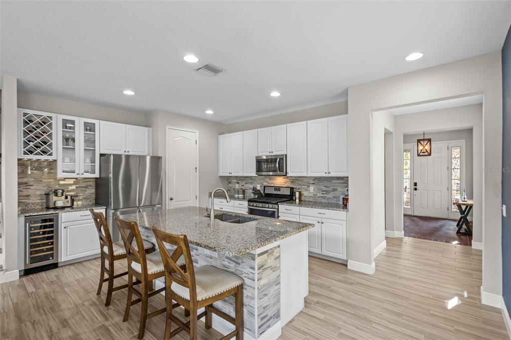 A kitchen with white cabinets, granite countertops, a center island, and a wine refrigerator — 14722 CARAVAN AVENUE, ODESSA, FL
