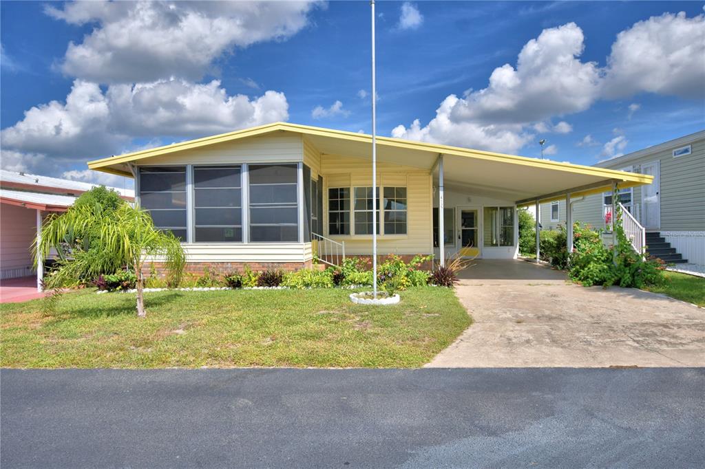 A yellow mobile home with a screened-in porch, carport, and a small front yard — 4127 SPRUCEWOOD STREET, WINTER HAVEN, FL