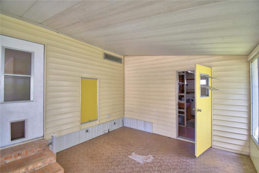 A covered porch with light yellow siding, a yellow door, and a pet door — 4127 SPRUCEWOOD STREET, WINTER HAVEN, FL