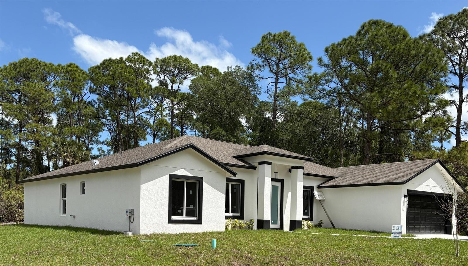 The rear exterior of a white stucco house features a covered patio and dark-framed windows — 471 Saul Road SW, Palm Bay FL 32908, PALM BAY, FL