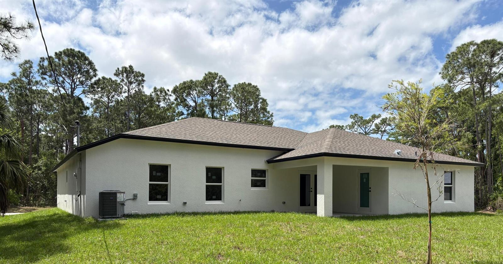 A modern open-concept kitchen and living area with white cabinets, marble island, and glossy floors — 471 Saul Road SW, Palm Bay FL 32908, PALM BAY, FL