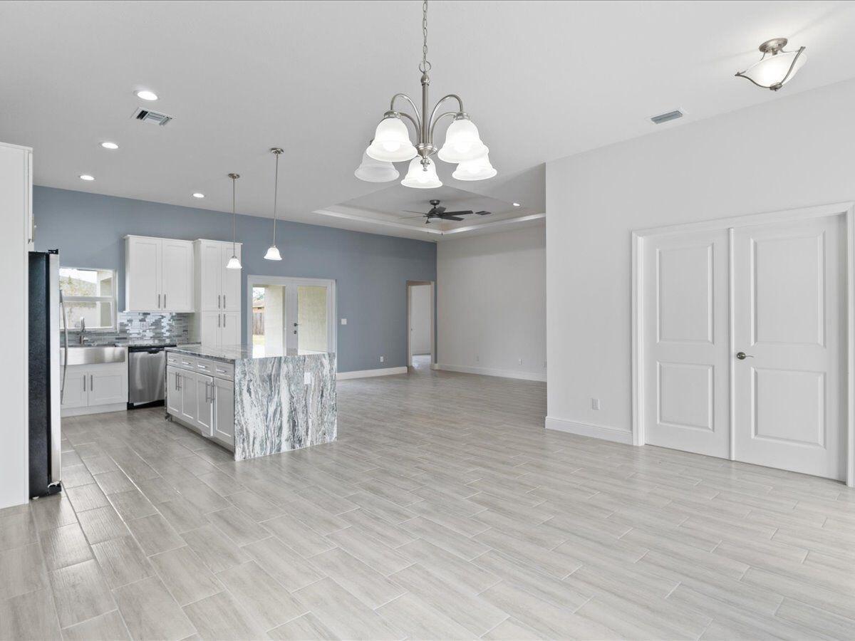 A hallway with white marble-patterned tile flooring leads to a bedroom and a bathroom door — 471 Saul Road SW, Palm Bay FL 32908, PALM BAY, FL