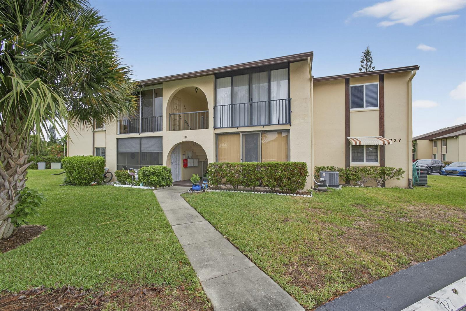 A two-story apartment building with a beige stucco exterior and a concrete walkway — 327 Pine Ridge Circle # 1, FL 33463, FL
