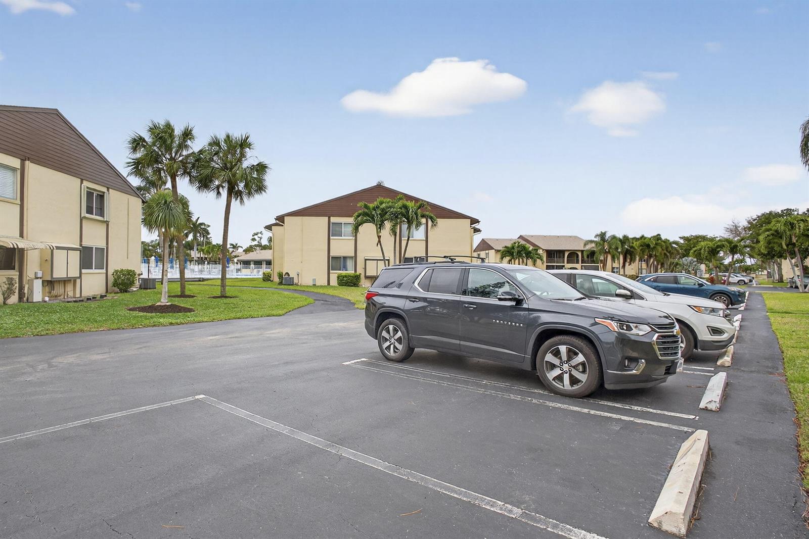 A parking lot with a dark SUV sits in front of two-story apartment buildings — 327 Pine Ridge Circle # 1, FL 33463, FL
