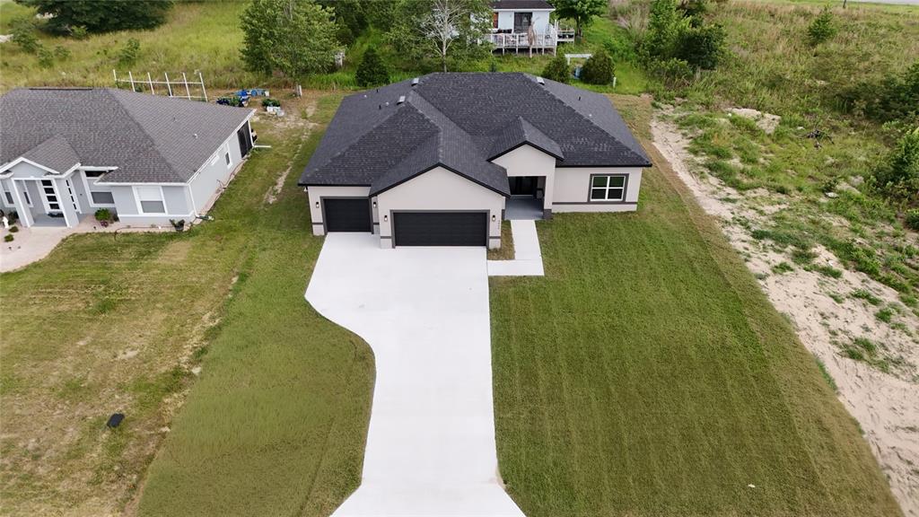 An aerial view shows a modern single-story house with a dark roof and concrete driveway — 4612 SW 132ND STREET, OCALA, FL