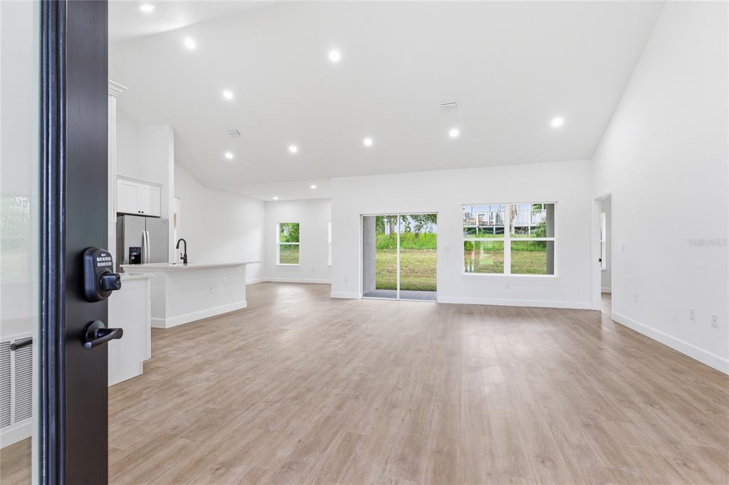 An open-concept living area features light wood-look flooring, white walls, recessed lighting, and a kitchen — 4612 SW 132ND STREET, OCALA, FL
