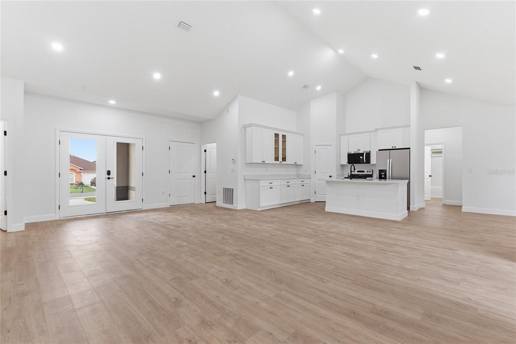 A bright, open-concept living area features white cabinetry, a kitchen island, and light wood flooring — 4612 SW 132ND STREET, OCALA, FL