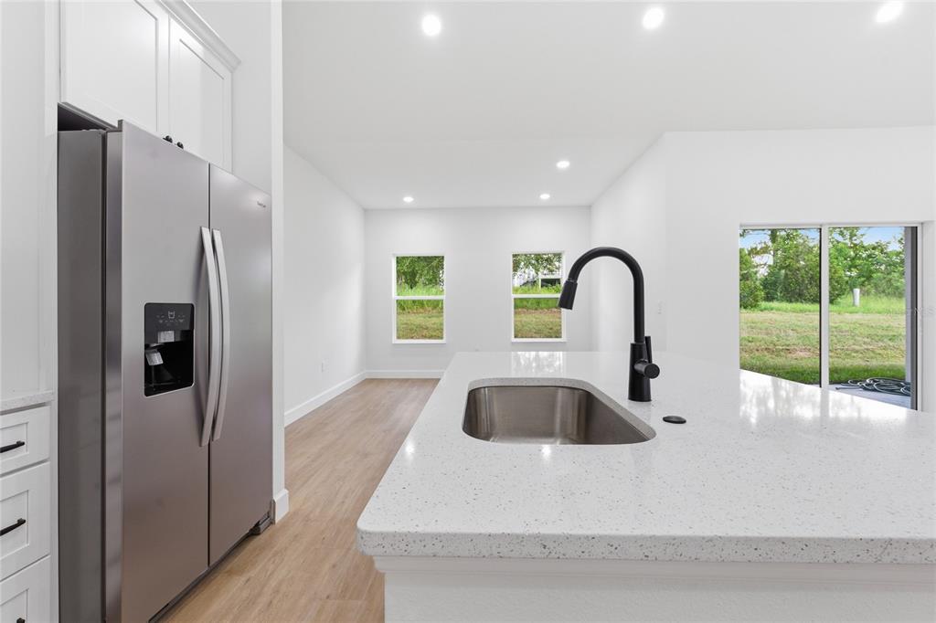 A kitchen features a stainless steel refrigerator, a white quartz island, and a black faucet — 4612 SW 132ND STREET, OCALA, FL