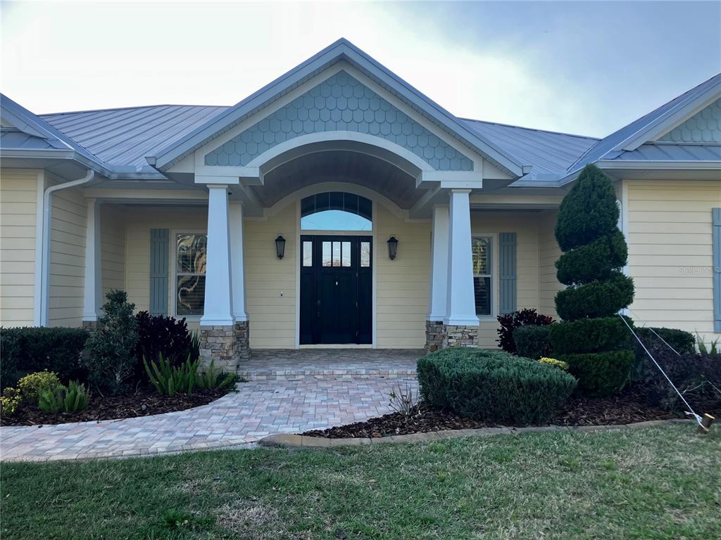 The exterior of a house features a covered entryway with columns and a metal roof — 3709 GALLAGHER ROAD, PLANT CITY, FL