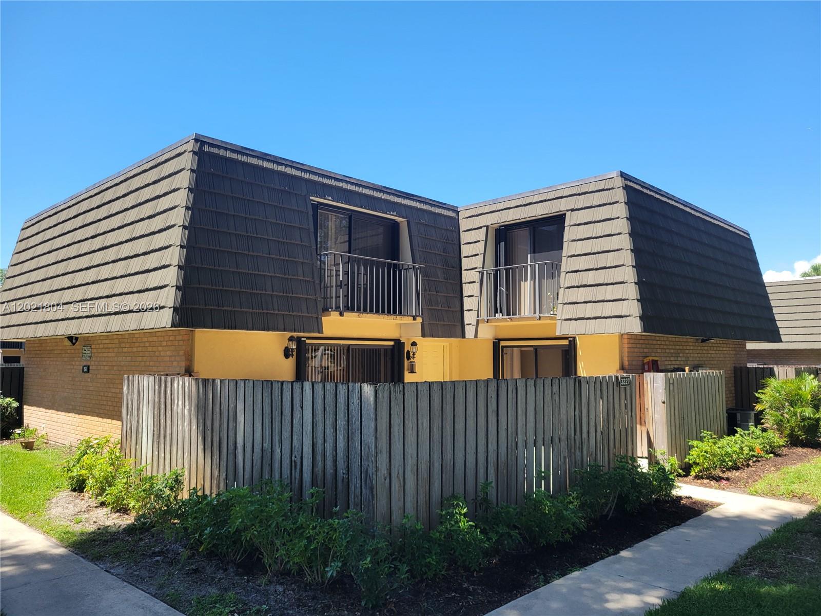 A two-story townhouse exterior features a mansard roof, private fenced patios, and a walkway — 3227 32nd Way # 3227, West Palm Beach FL 33407, WEST PALM BEACH, FL