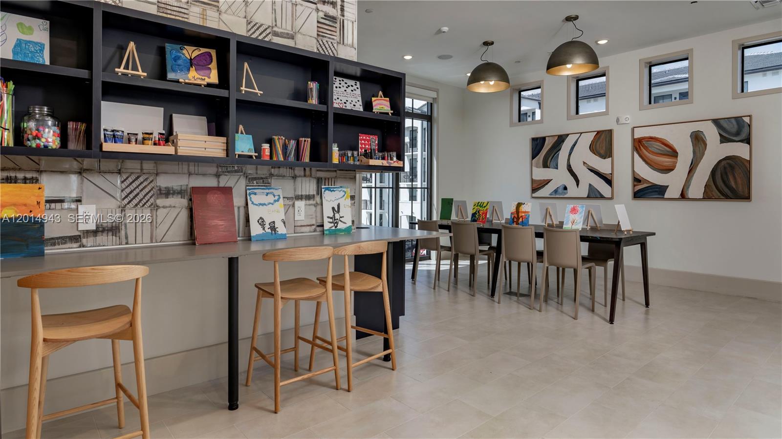 This art studio features built-in shelving, a long workspace with wooden stools, and dining tables — 9030 SW 158th Ave # 209, Miami FL 33196, MIAMI, FL