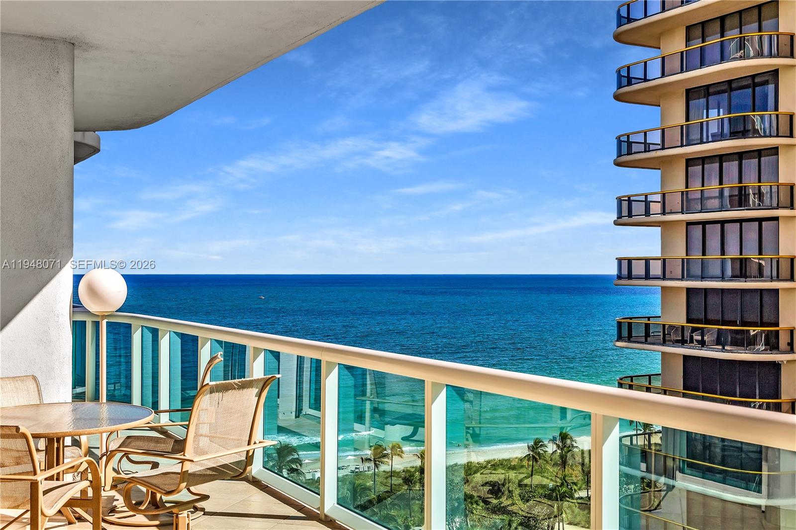 A balcony with patio furniture overlooks the ocean and a neighboring high-rise building — 10101 Collins Ave, Bal Harbour FL 33154, BAL HARBOUR, FL