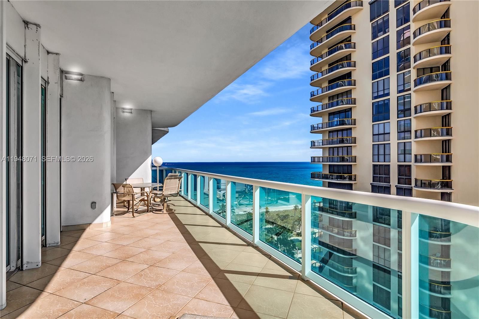 A spacious balcony features tiled flooring, a glass railing, and an expansive ocean view — 10101 Collins Ave, Bal Harbour FL 33154, BAL HARBOUR, FL