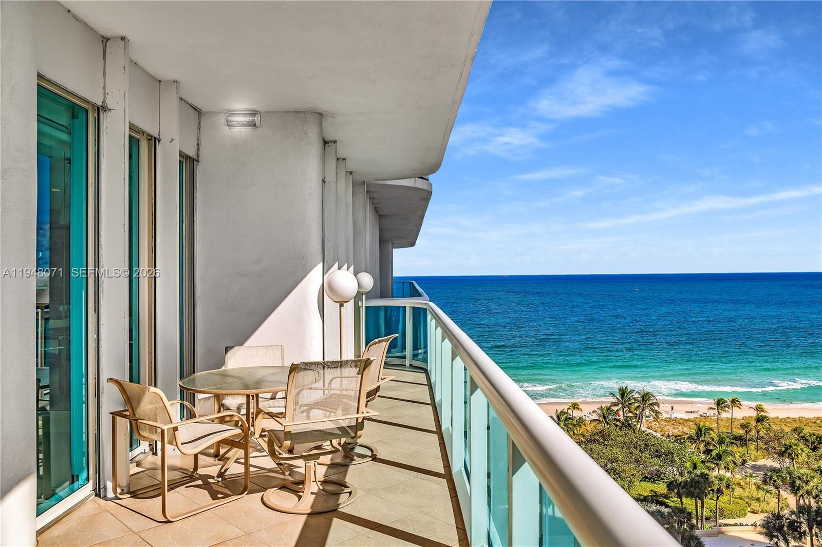 A balcony with patio furniture overlooks the ocean and a sandy beach — 10101 Collins Ave, Bal Harbour FL 33154, BAL HARBOUR, FL