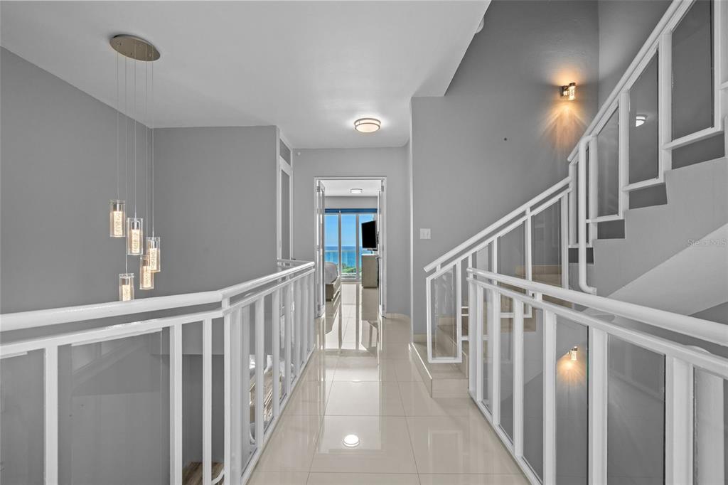 A hallway with white railings leads toward a bedroom with a view of the ocean — 1 SHELL CASTLE CLUB UNIT 74, HUMACAO, PR