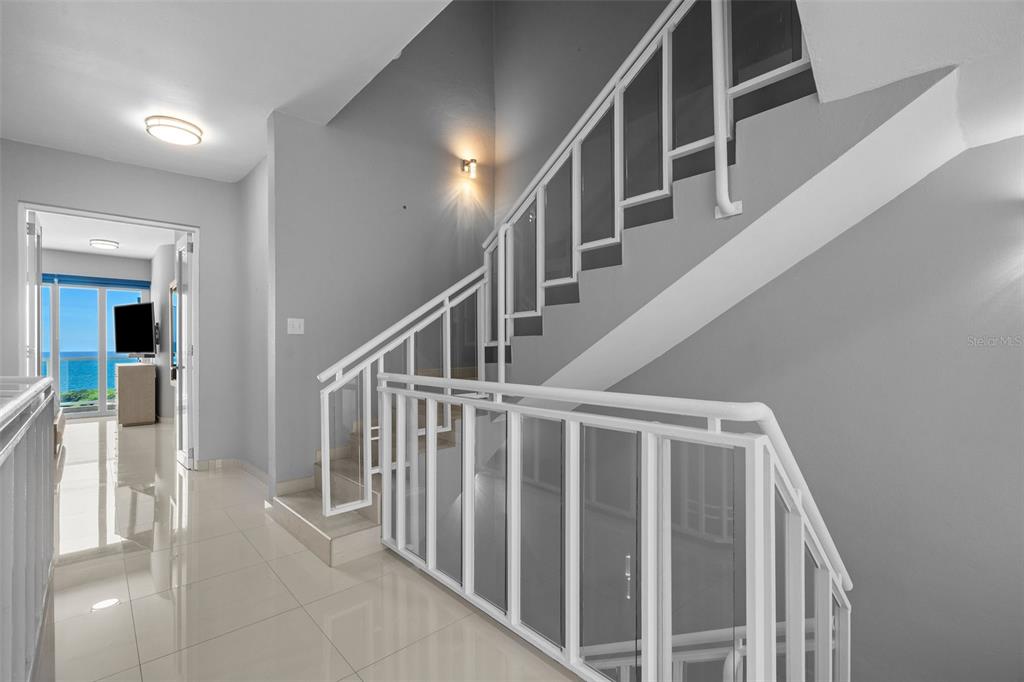 A staircase with white railings and glass panels leads upward in a modern interior — 1 SHELL CASTLE CLUB UNIT 74, HUMACAO, PR