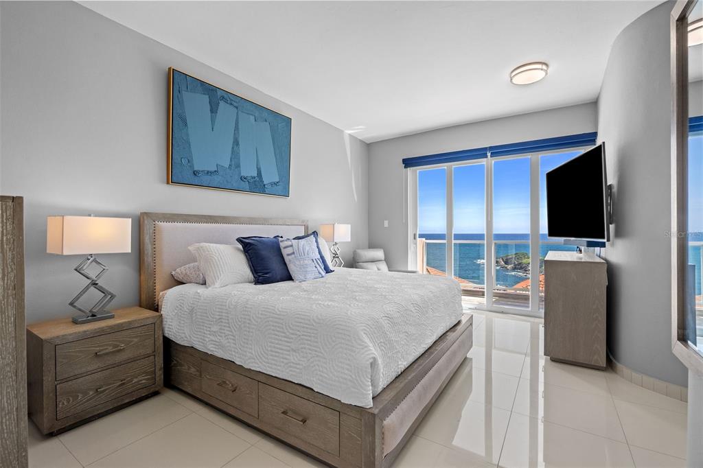 A bedroom with a king bed, wooden furniture, and a balcony overlooking the ocean — 1 SHELL CASTLE CLUB UNIT 74, HUMACAO, PR