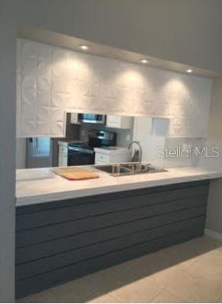 A kitchen pass-through window features white embossed panels above a dark gray shiplap breakfast bar — 2963 GLEN HAVEN DRIVE, PALM HARBOR, FL