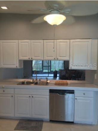A kitchen features white cabinets, a stainless steel dishwasher, and a window overlooking a patio — 2963 GLEN HAVEN DRIVE, PALM HARBOR, FL