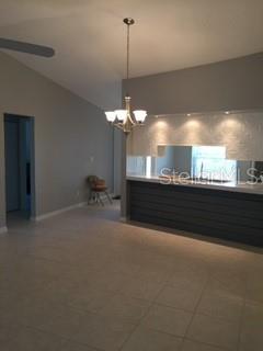 A dining area with a chandelier, tiled floors, and a kitchen pass-through with a mirror — 2963 GLEN HAVEN DRIVE, PALM HARBOR, FL