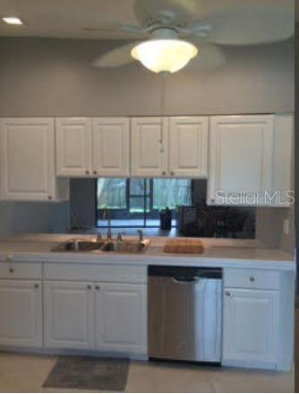 A kitchen features white cabinets, a stainless steel dishwasher, and a double-basin sink — 2963 GLEN HAVEN DRIVE, PALM HARBOR, FL