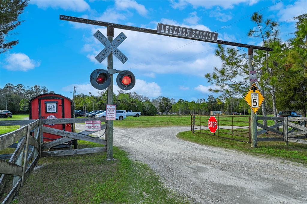 An entrance gate features a railroad crossing sign and a Lebanon Station sign above it — 11350 STATE ROAD 121, INGLIS, FL