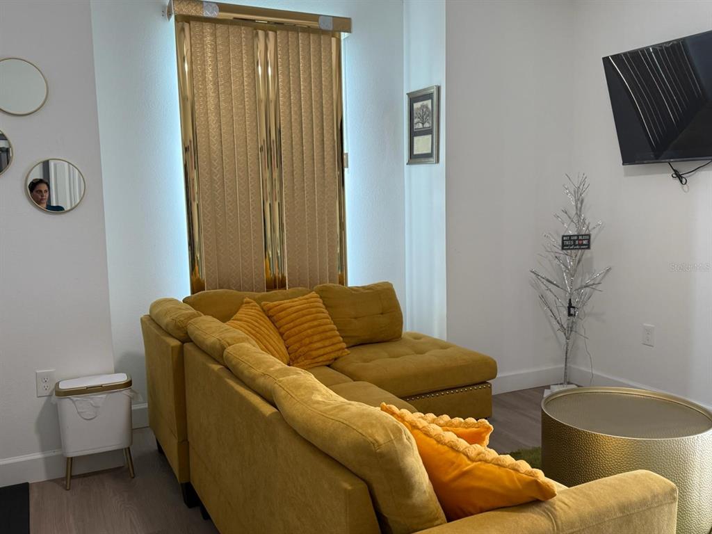 A living room features a mustard yellow sectional sofa, a gold coffee table, and vertical blinds — 2050 FLORIDA DEVELOPMENT ROAD UNIT A, DAVENPORT, FL