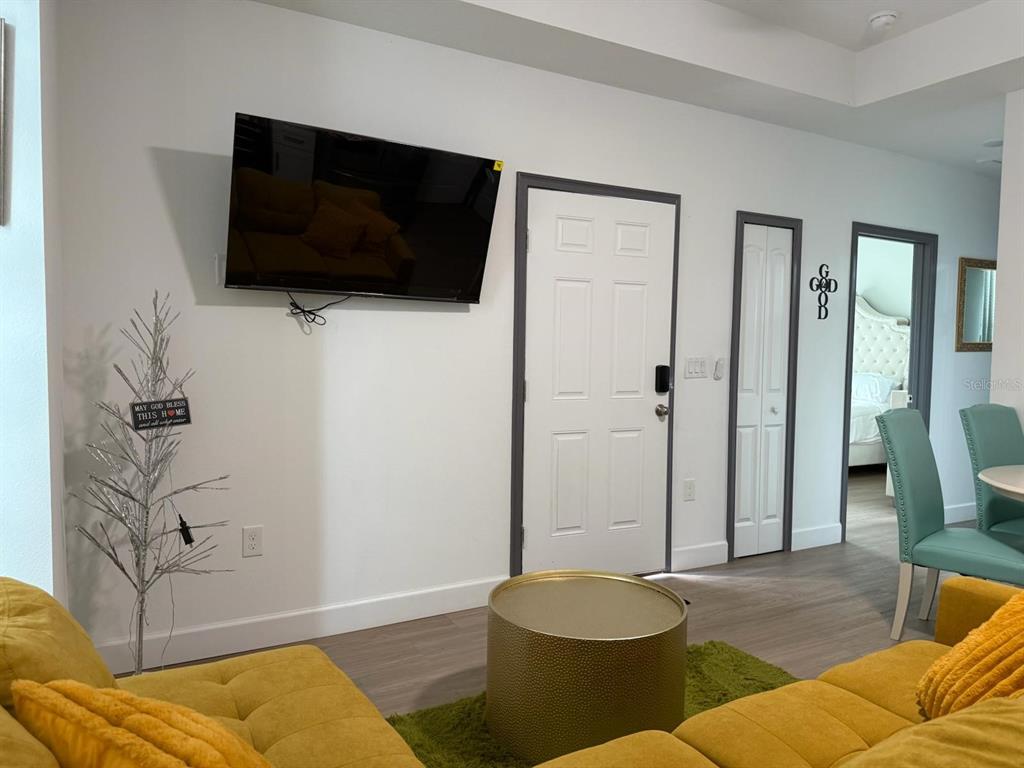 A living room features a wall-mounted television, a yellow sofa, and a gold coffee table — 2050 FLORIDA DEVELOPMENT ROAD UNIT A, DAVENPORT, FL